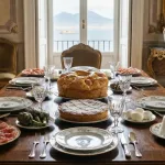 Una mesa festiva rebosante de la tradicional comida de Semana Santa en Nápoles, destacando en el centro un Casatiello salado y una dulce Pastiera.
