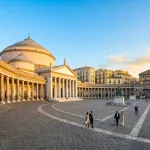 La imponente Plaza del Plebiscito iluminada durante la hora dorada, uno de los lugares imprescindibles en Nápoles.